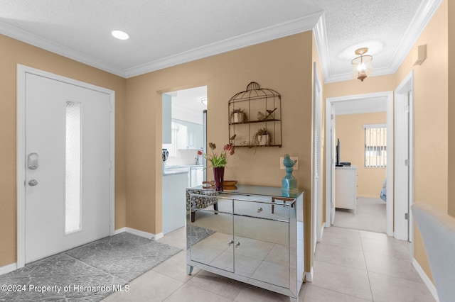 tiled entrance foyer featuring a textured ceiling and crown molding