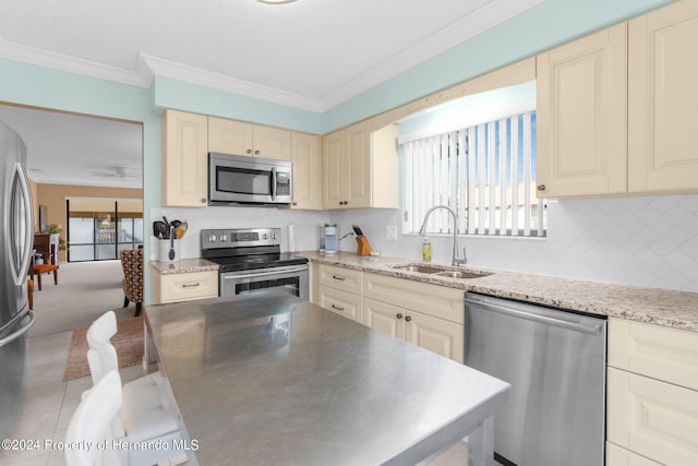 kitchen with sink, cream cabinets, crown molding, and stainless steel appliances