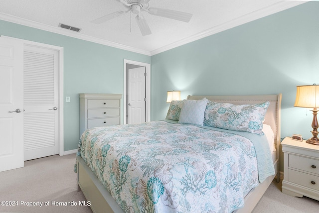 carpeted bedroom with ornamental molding, a closet, and ceiling fan