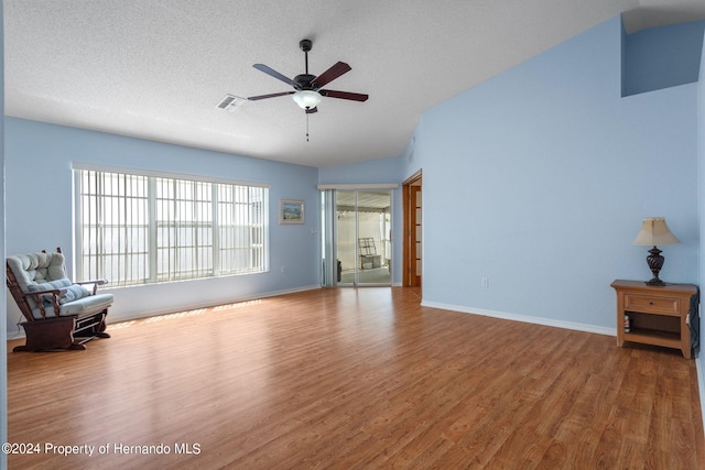 living room featuring hardwood / wood-style floors, ceiling fan, and a textured ceiling