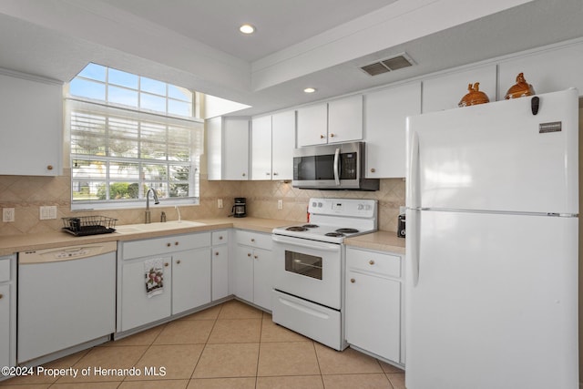 kitchen featuring sink, tasteful backsplash, light tile patterned floors, white cabinetry, and white appliances