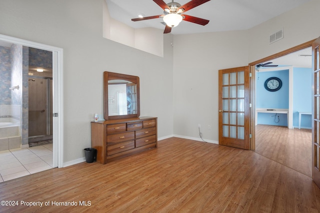 interior space featuring ensuite bathroom, french doors, a high ceiling, and light hardwood / wood-style flooring