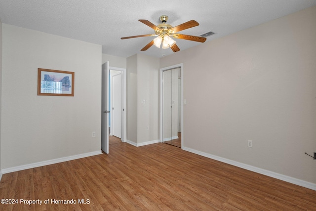 spare room featuring a textured ceiling, light hardwood / wood-style flooring, and ceiling fan