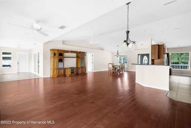 unfurnished living room with dark wood-type flooring, lofted ceiling, and a healthy amount of sunlight