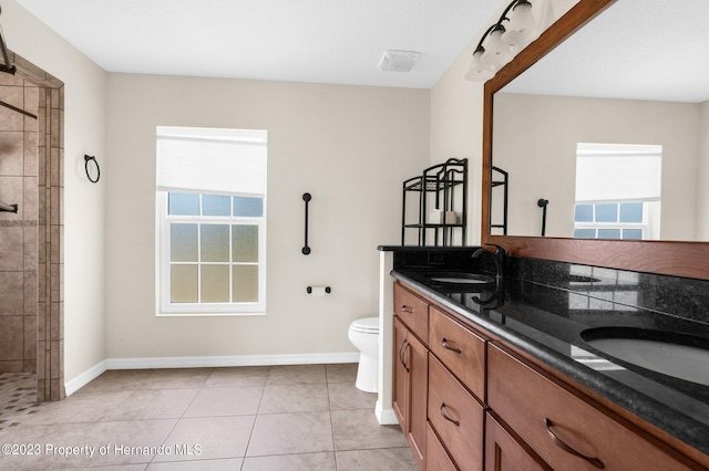 bathroom featuring toilet, vanity, tile patterned floors, and a tile shower