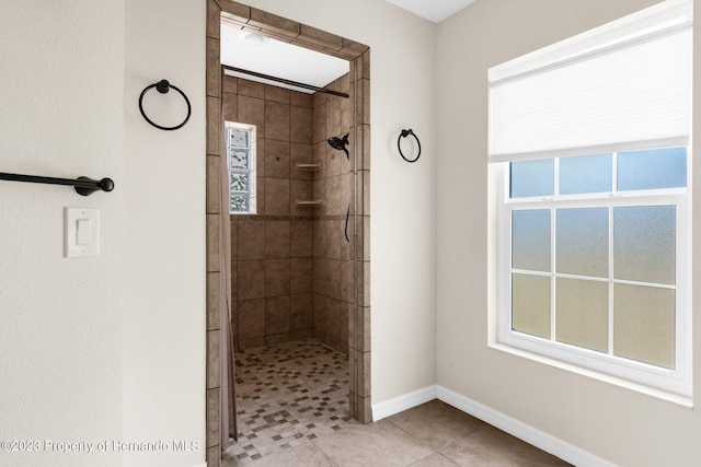 bathroom with a tile shower and tile patterned floors