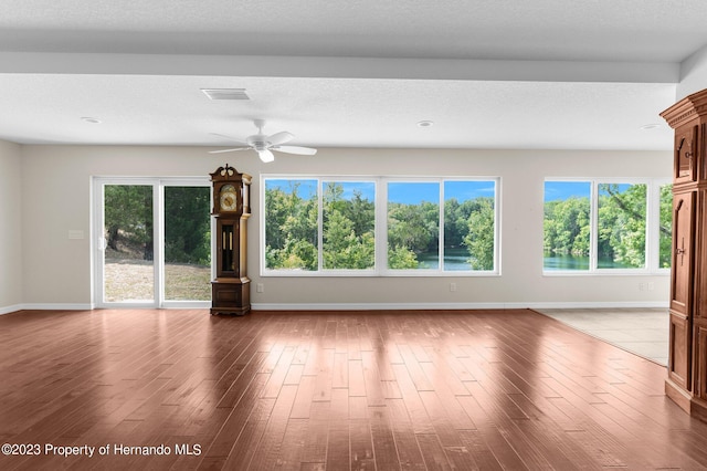 unfurnished living room featuring hardwood / wood-style flooring, ceiling fan, and a textured ceiling