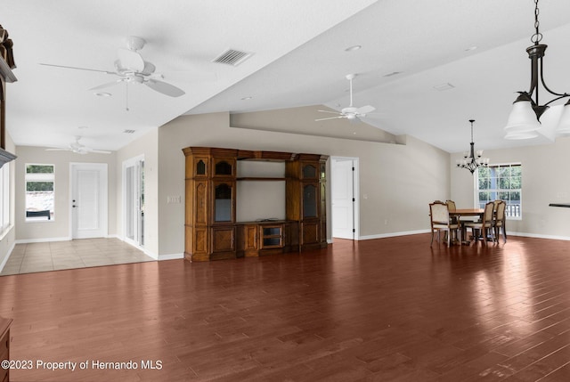 unfurnished living room with dark wood-type flooring, a wealth of natural light, a chandelier, and vaulted ceiling