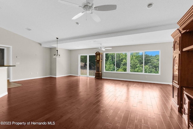 unfurnished living room with dark wood-type flooring, a textured ceiling, ceiling fan with notable chandelier, and plenty of natural light