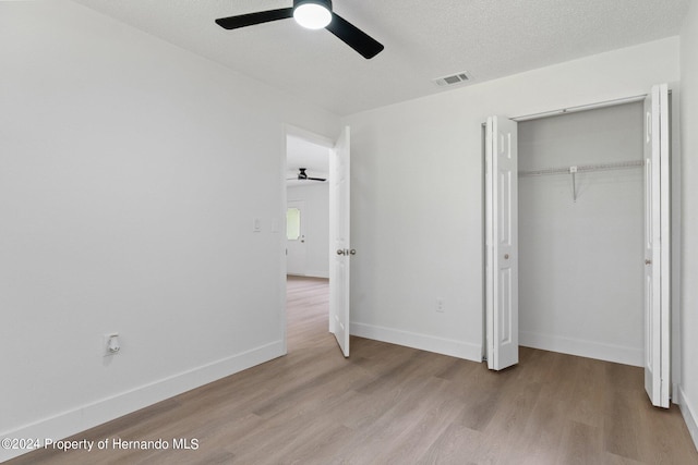 unfurnished bedroom with light hardwood / wood-style floors, ceiling fan, a textured ceiling, and a closet