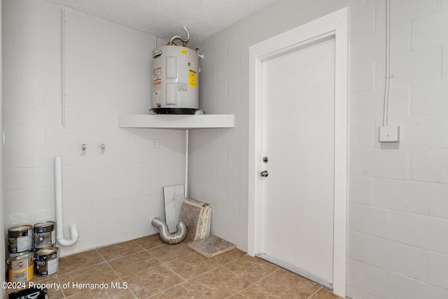 washroom featuring electric water heater, a textured ceiling, and light tile patterned floors