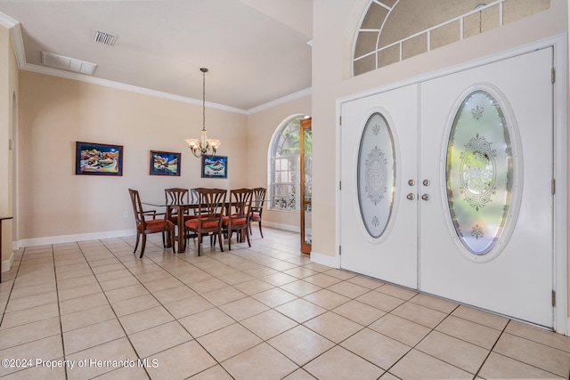 foyer entrance with light tile patterned flooring, an inviting chandelier, and ornamental molding