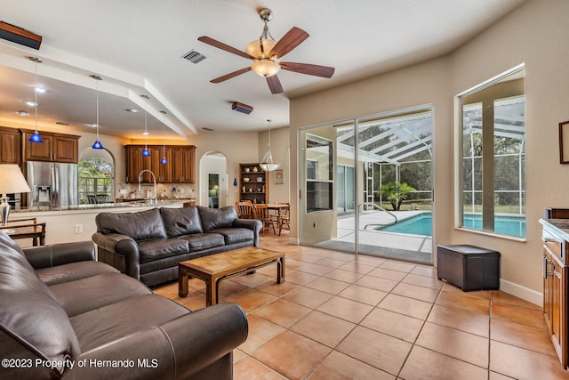 tiled living room with ceiling fan, a healthy amount of sunlight, and beam ceiling