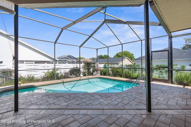 view of pool with glass enclosure and a patio