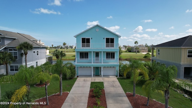 coastal inspired home featuring a garage, a front yard, and a balcony