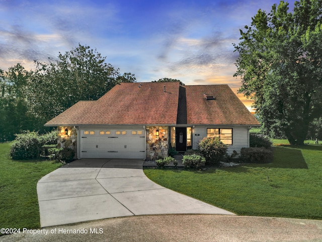 view of front of property with a garage and a yard