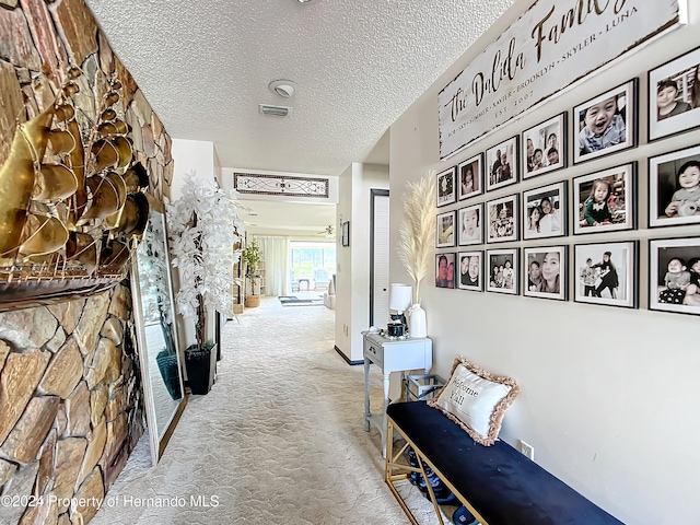 hall with light colored carpet and a textured ceiling