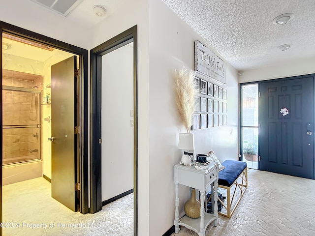 entryway with a textured ceiling and light carpet