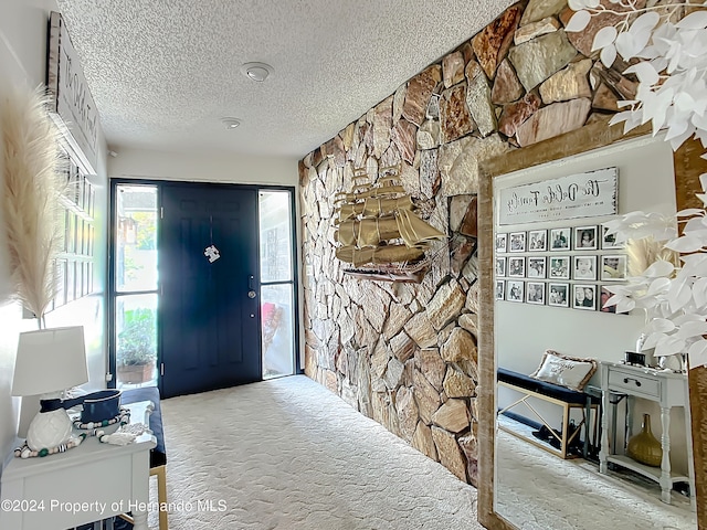 entryway featuring a textured ceiling and carpet flooring