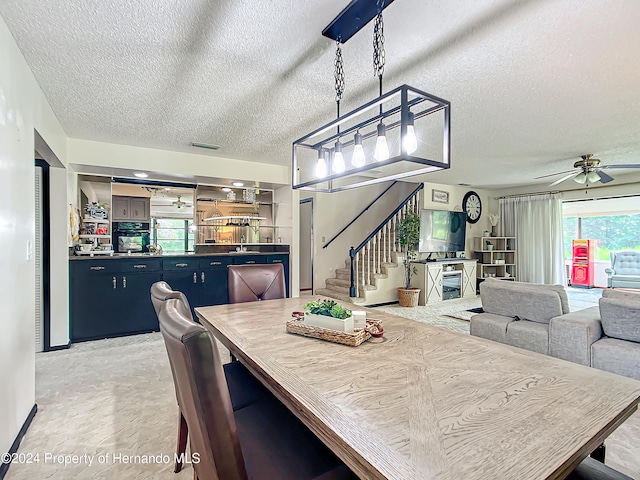 dining space featuring a textured ceiling, ceiling fan, and a fireplace