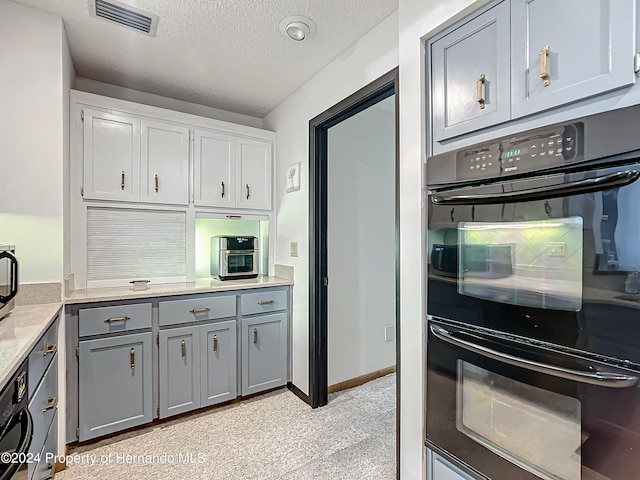 kitchen featuring gray cabinetry, black double oven, a textured ceiling, and white cabinetry