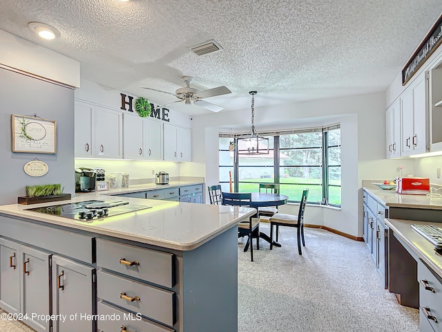 kitchen with hanging light fixtures, a textured ceiling, and white cabinets