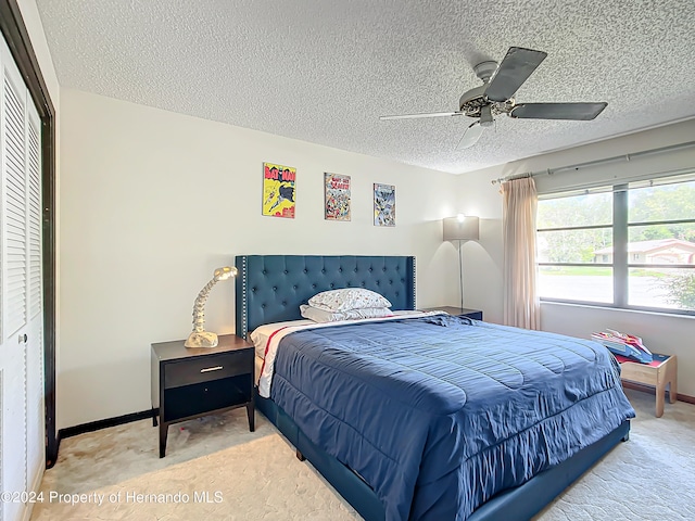 bedroom featuring ceiling fan, a textured ceiling, a closet, and carpet flooring