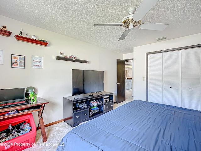 carpeted bedroom featuring ceiling fan, a textured ceiling, and a closet