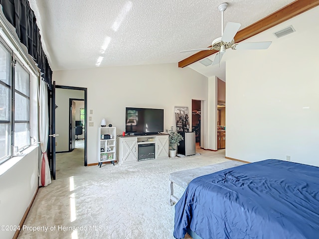 bedroom featuring lofted ceiling with beams, a textured ceiling, light carpet, and ceiling fan