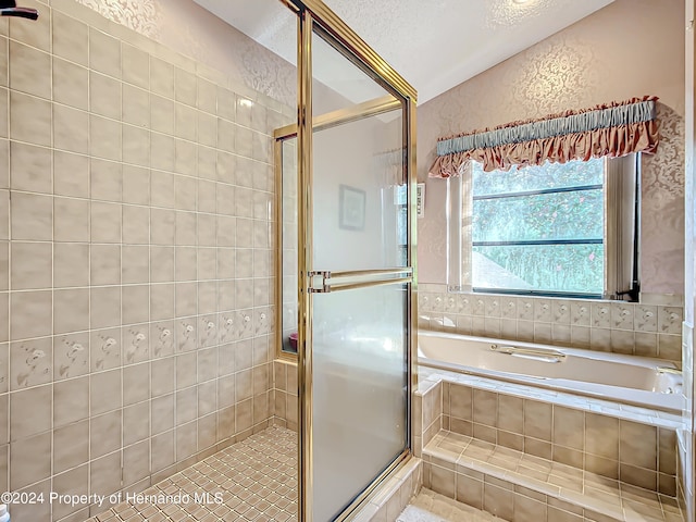 bathroom with a textured ceiling and separate shower and tub