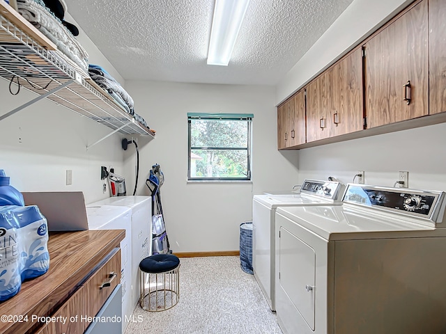 washroom featuring washing machine and clothes dryer, cabinets, a textured ceiling, and light carpet