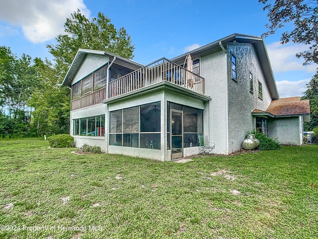 rear view of property with a lawn and a sunroom