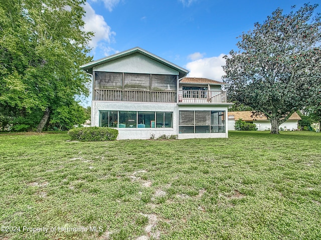 back of house with a sunroom, a yard, and a balcony