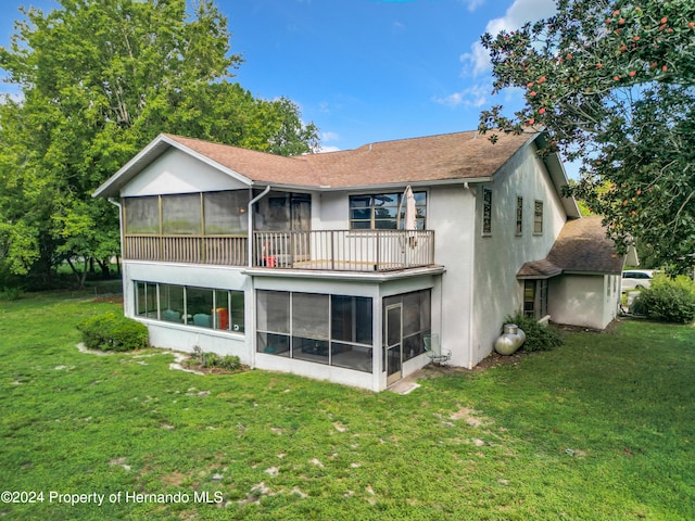 back of house featuring a balcony, a sunroom, and a yard