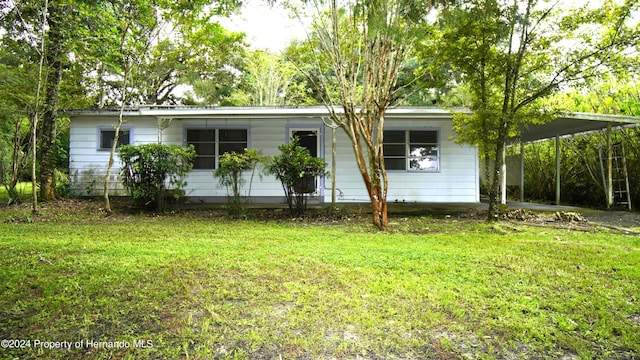 back of house featuring a carport and a lawn