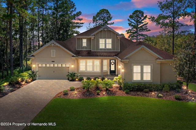 craftsman inspired home featuring a garage and a yard