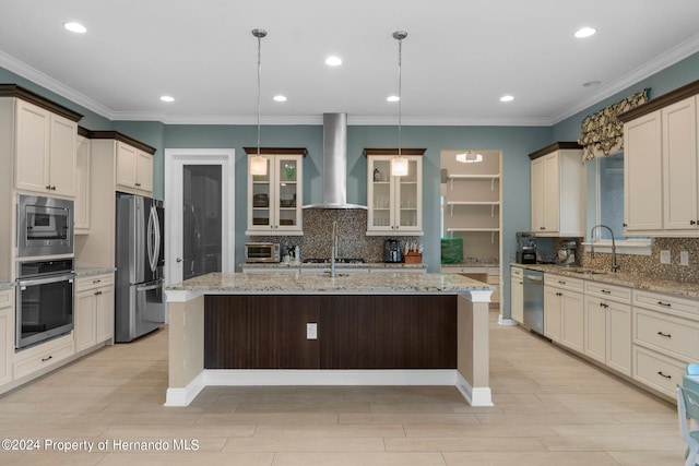 kitchen with stainless steel appliances, sink, wall chimney exhaust hood, decorative light fixtures, and an island with sink