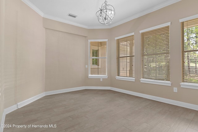 empty room featuring a chandelier, light wood-type flooring, and ornamental molding