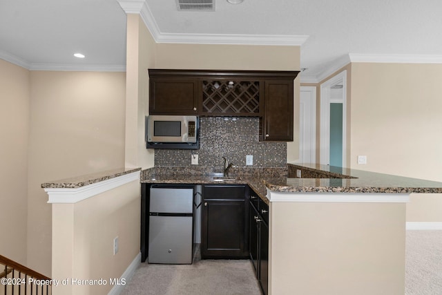 kitchen with stainless steel appliances, kitchen peninsula, tasteful backsplash, dark stone counters, and light colored carpet