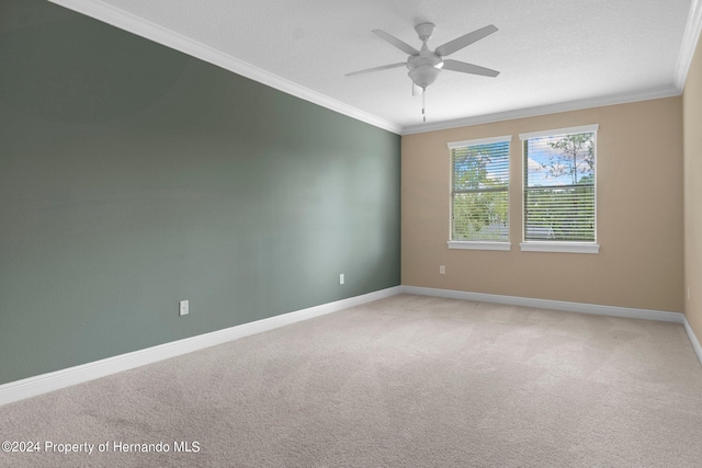 carpeted spare room featuring ceiling fan and crown molding