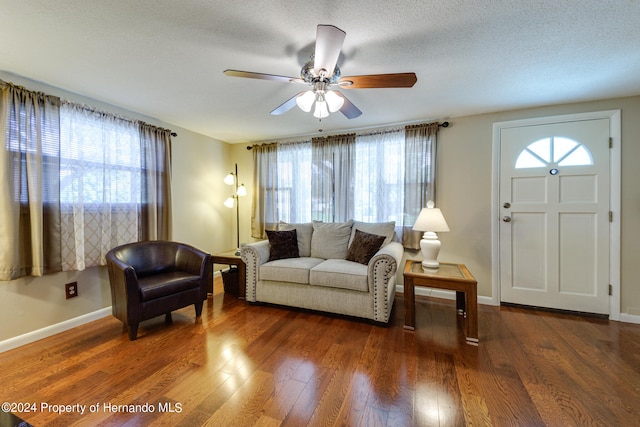 living room featuring a textured ceiling, dark wood-type flooring, and ceiling fan