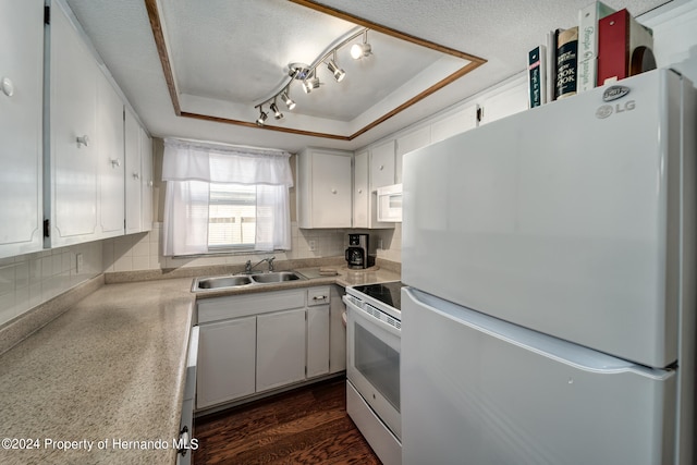 kitchen featuring white cabinets, sink, tasteful backsplash, a tray ceiling, and white appliances