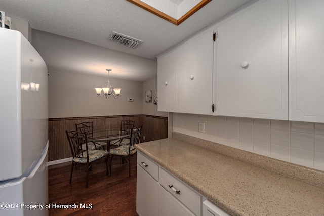 kitchen featuring a notable chandelier, white cabinets, wooden walls, white fridge, and dark wood-type flooring