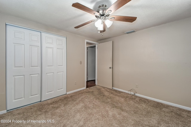 unfurnished bedroom with a closet, a textured ceiling, light colored carpet, and ceiling fan