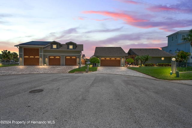 view of front of property featuring a lawn, a garage, and solar panels