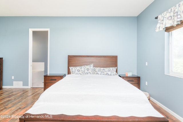 bedroom with hardwood / wood-style flooring and connected bathroom