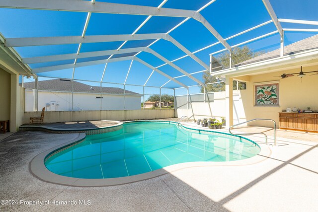 view of swimming pool with ceiling fan, a lanai, and a patio