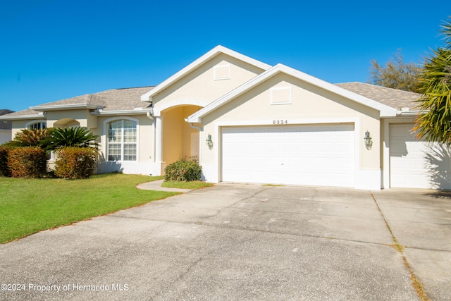 single story home featuring a garage and a front lawn