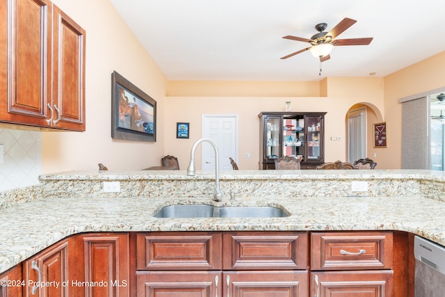 kitchen with light stone countertops, decorative backsplash, sink, stainless steel dishwasher, and ceiling fan