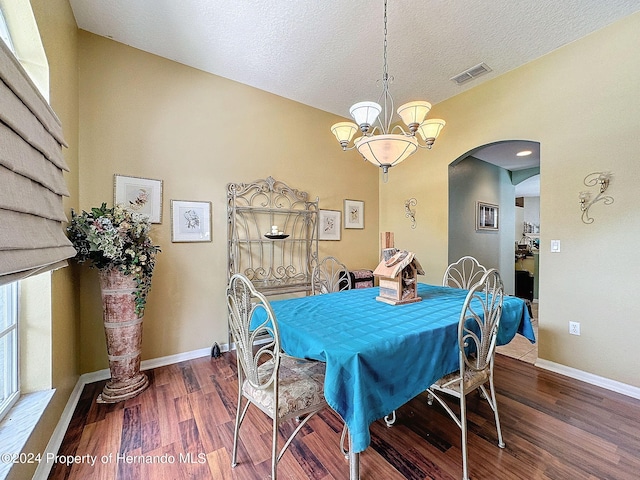 dining room with wood-type flooring, a textured ceiling, and an inviting chandelier